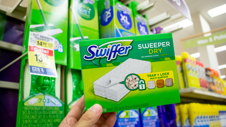 A hand grabs a pack of Swiffer pads from the store.