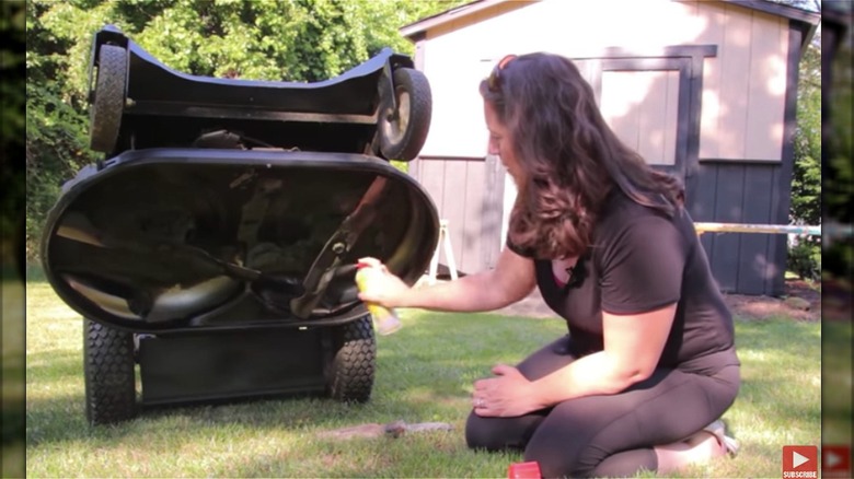woman sprays mower with oil