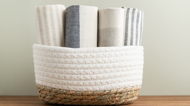 Rolled tea towels inside of woven basket