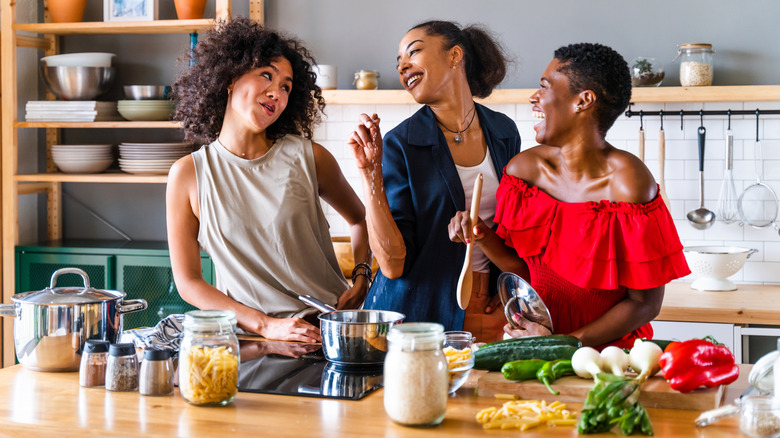 People laughing and cooking together in a kitchen with fresh ingredients