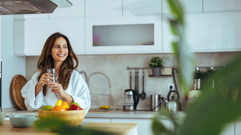 A person smiling while drinking coffee in a modern kitchen