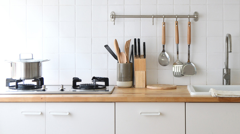 kitchen utensils in a crock and hanging from wall hooks