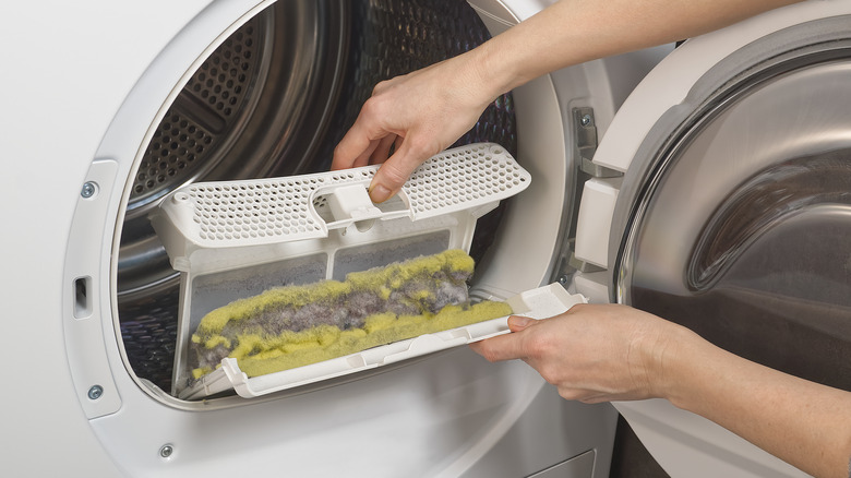 Hands opening dryer lint trap