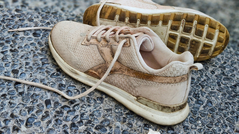 Dirty old sneakers on a gray pebble floor