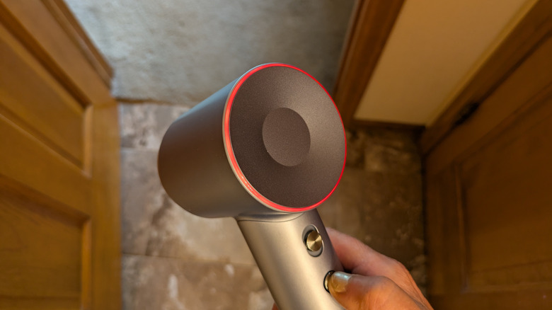 A hand adjusts the heat setting on a hair dryer.