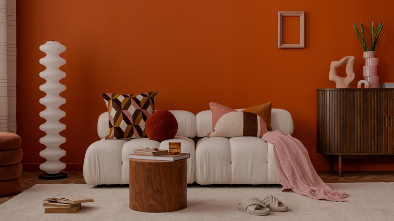 Mid-century modern living room with orange walls and rounded white sofa