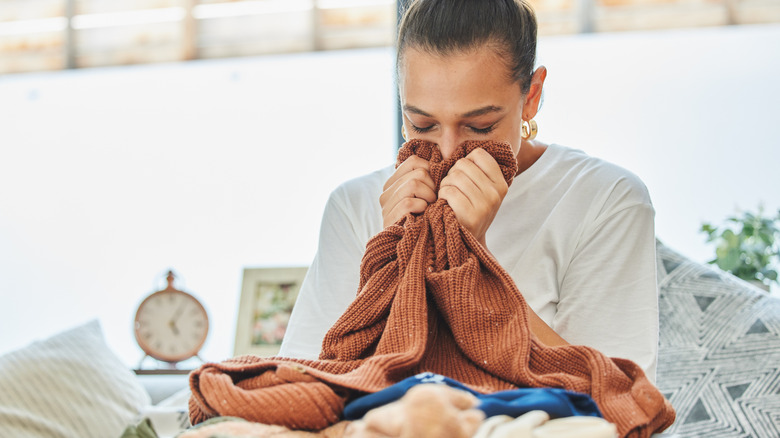 A woman smells clothes that have just come out of the dryer