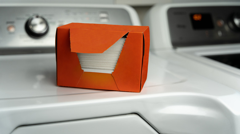 An orange box of dryer sheets sits on a white washing machine, ready to help homes smell clean.