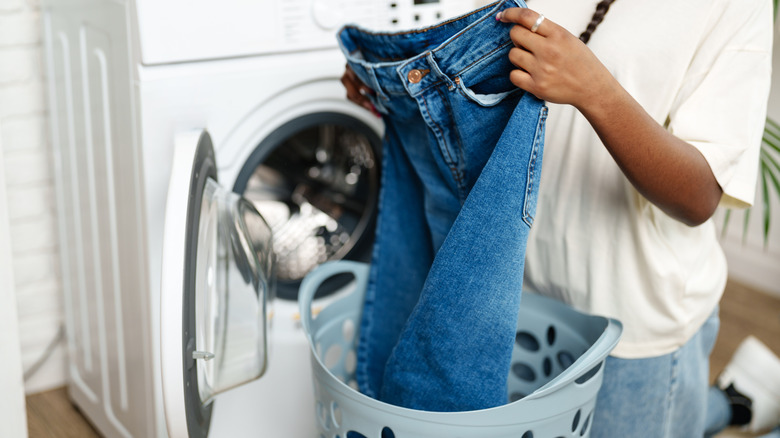 Woman holding a pair of jeans with a zipped zipper and fastened button
