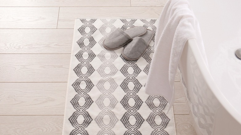 slippers on grayscale patterned bathroom rug in front of tub