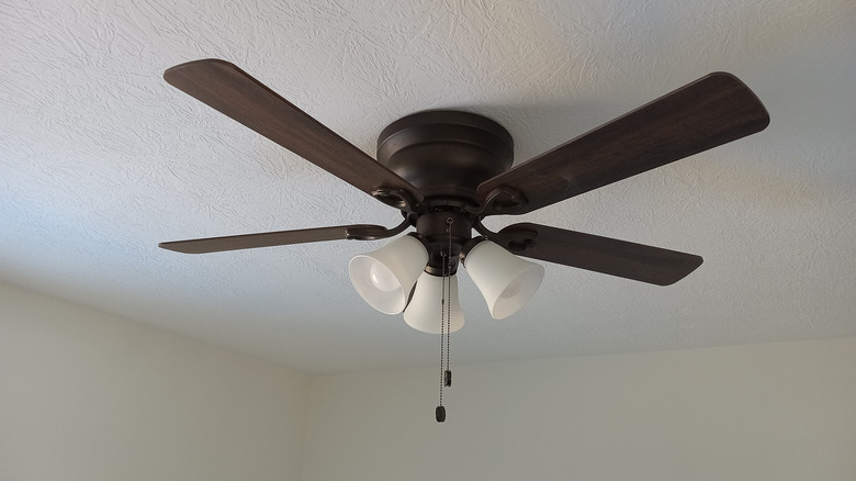 A brown ceiling fan with lights installed in a small laundry room.