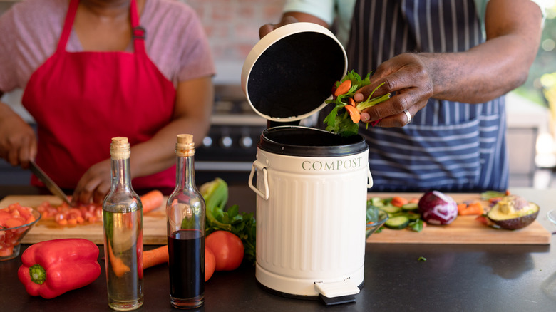 Couple cooking with compost bin in foreground on countertop