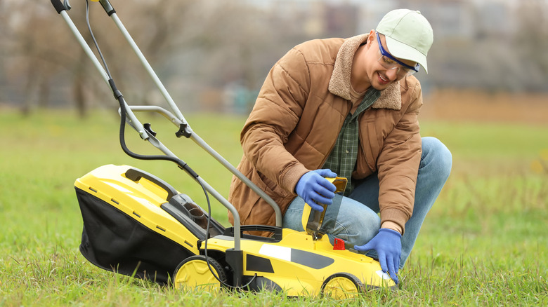 A man checking a part on his push mower