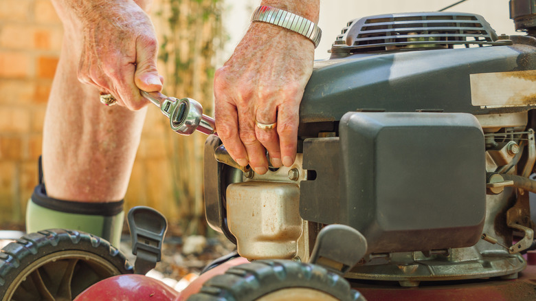 A person replacing a spark plug on their mower