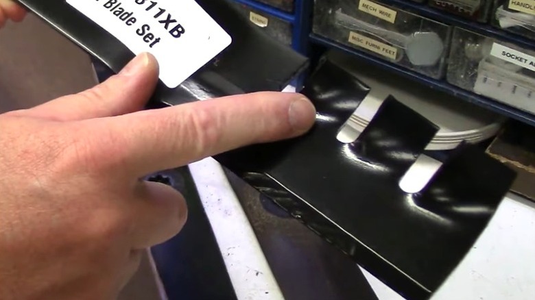 Person pointing at cutting teeth on mulching mower blade