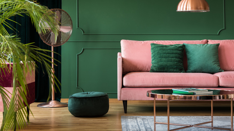 A maximalist living room with emerald green walls and a salmon pink couch
