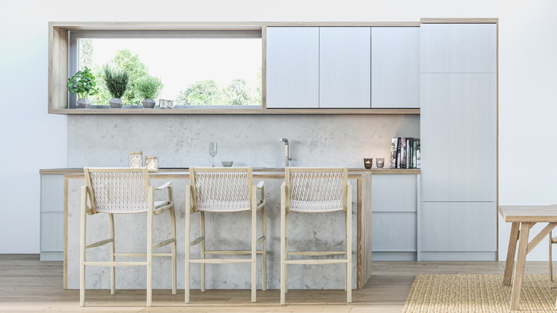 Three chairs at a stone kitchen island in a kitchen with light blue cabinets