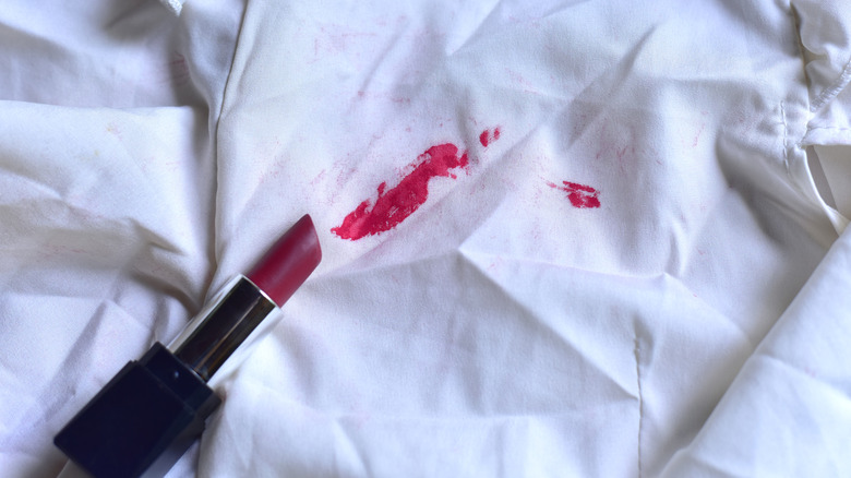 Red lipstick tube with stain on white shirt