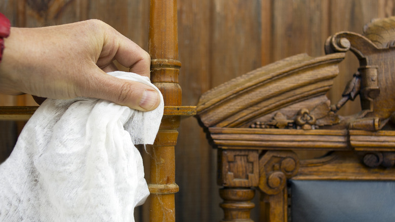 Antique wooden furniture is wiped down by a clean, white cloth.