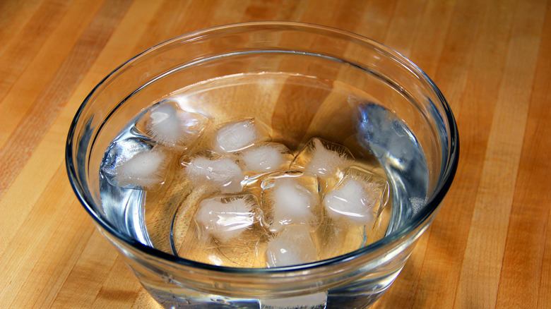 A bowl of ice water on a table.