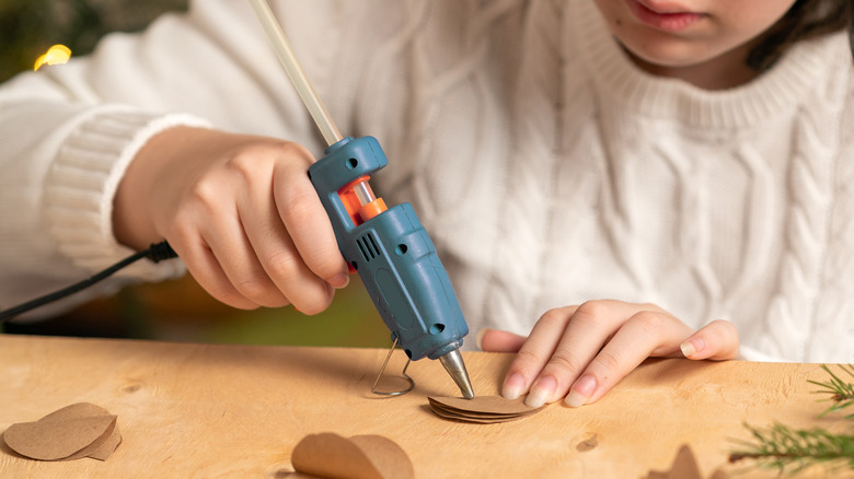 A woman uses a hot glue gun to make a paper craft.