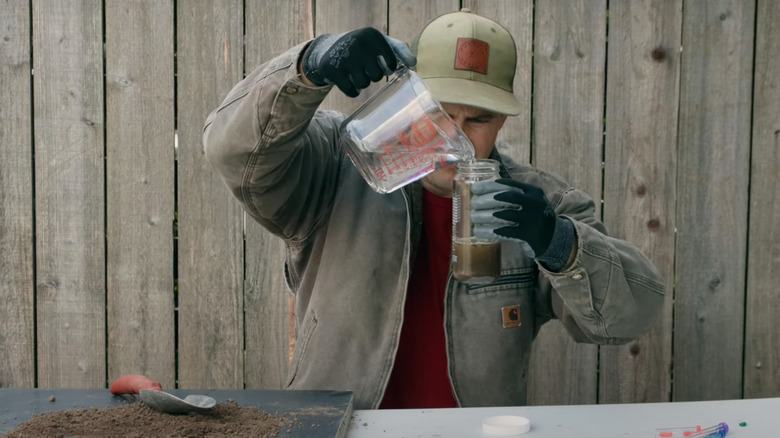A person mixing a DIY soil test in a jar