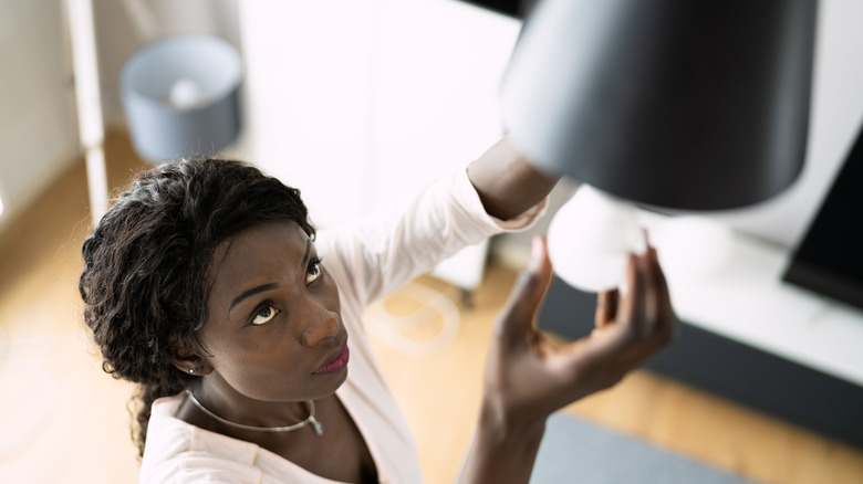 A woman changes an LED lightbulb in an overhead fixture