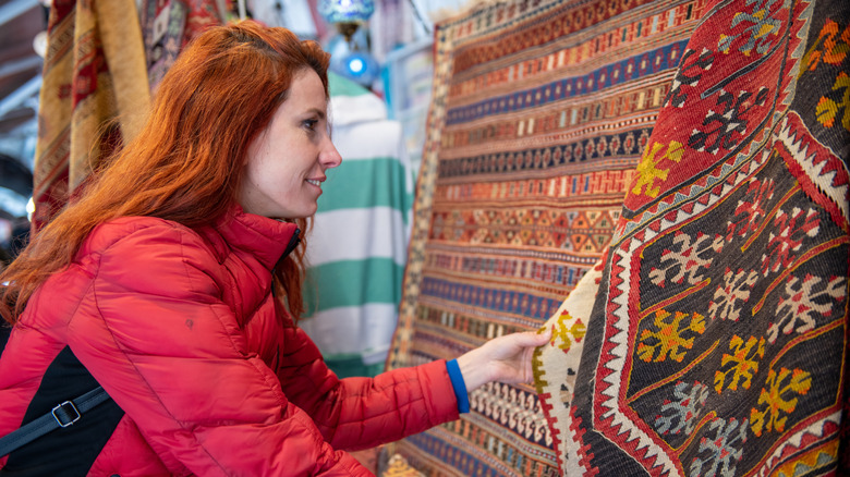A woman looking at vintage carpets for sale