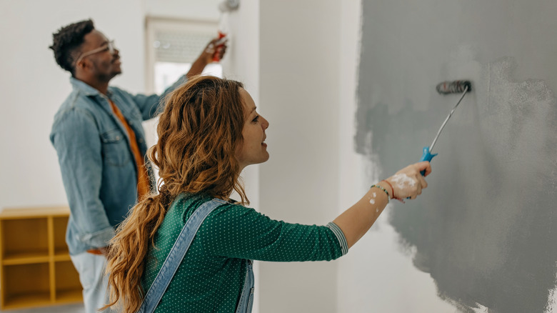 Man and woman painting wall