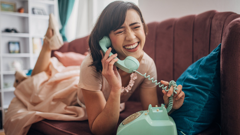 A person uses a light green landline phone