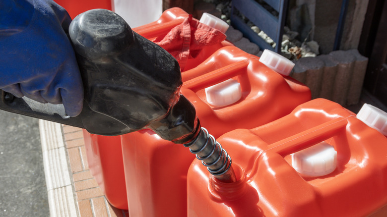 A person filling multiple gas cans