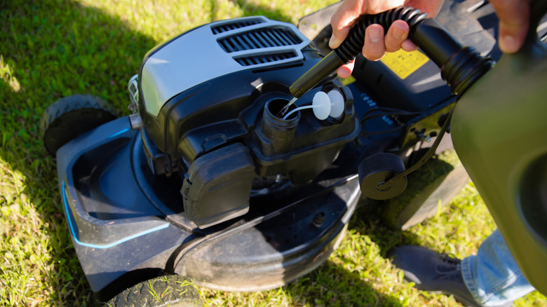 Close up of a person filling a mower's gas tank