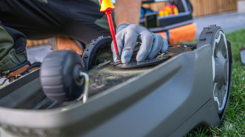 A person is doing some maintenance work on a lawn mower