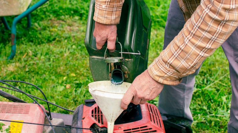 A man fills the lawnmower with gasoline