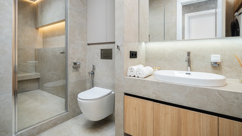 A contemporary bathroom with large beige tiles.