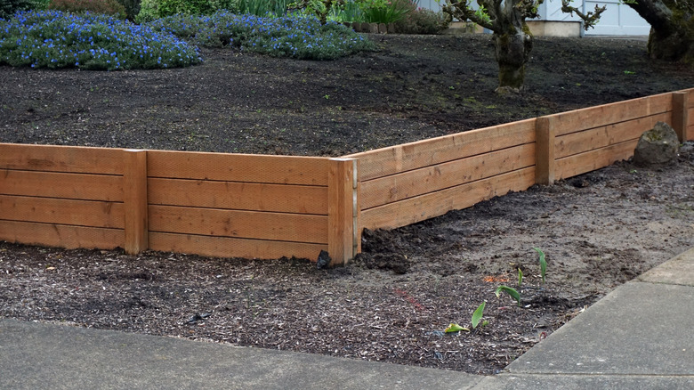A front yard with a timber retaining wall and ground cover plants to combat soil erosion