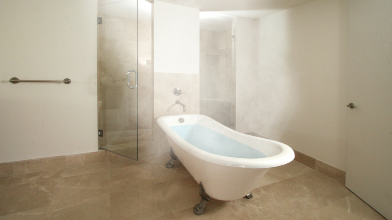 A modern minimalist bathroom with a shower and tub full of steam.