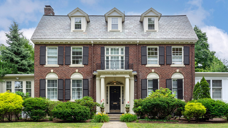 An elegant home has a variety of shrubs in its front yard.