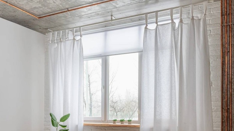 Knotted white sheer curtains against a window