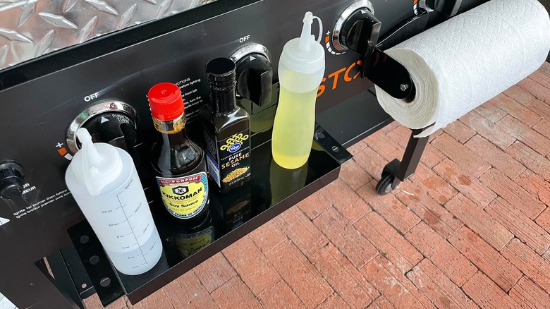 A black magnetic tray from Harbor Freight is attached to a grill, covered with oils and soy sauce.