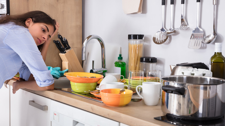 A tired woman looking at kitchen clutter