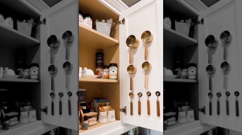 Metal measuring cups stuck to button magnets inside a cupboard