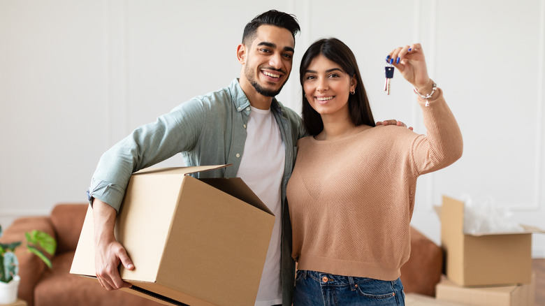 couple holding keys with moving boxes