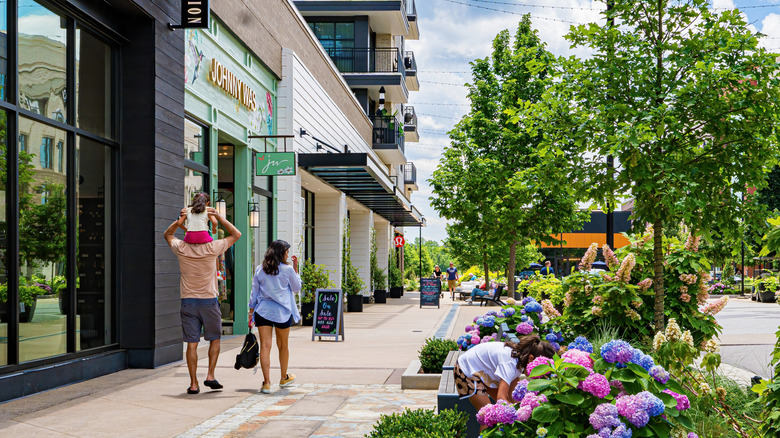 Family walks down the street by shops in a mixed-use development with apartments and condos