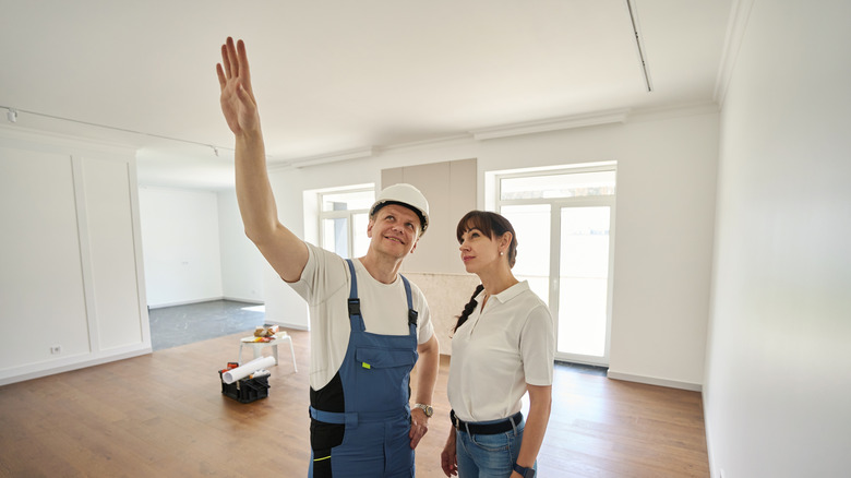 woman and male worker looking up at a ceiling