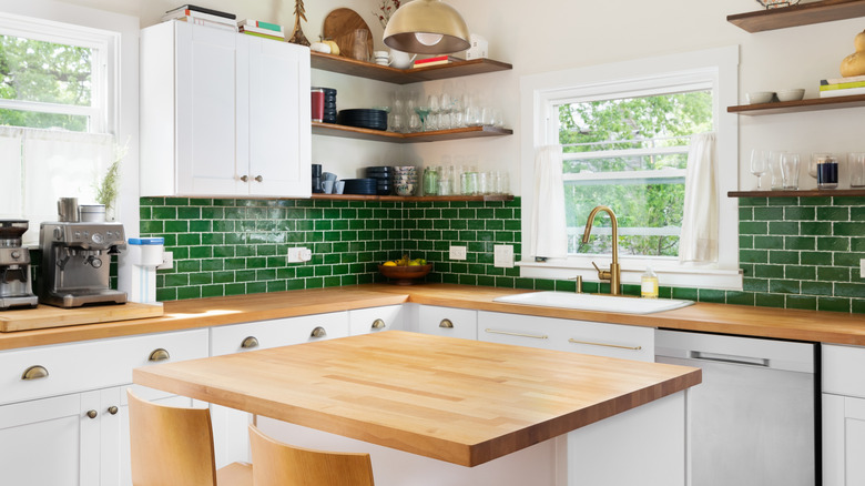 A kitchen with butcher block wood countertops and green subway tile backsplash
