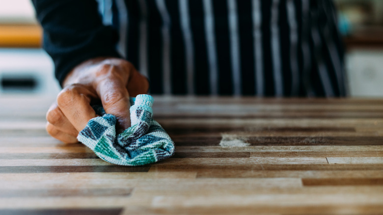 Person cleans butcher block with soft blue towel