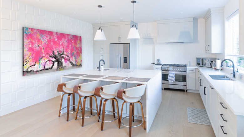 light open plan kitchen with pink tree art on wall away from the sink and oven