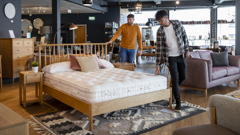Two men viewing a mattress in a home furniture showroom.