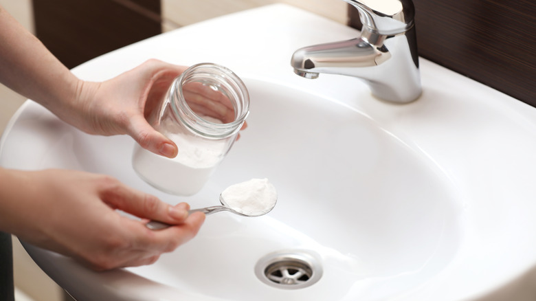 Spooning baking soda into sink